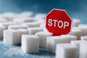 A red STOP sign placed among a collection of white sugar cubes, warning against excessive consumption