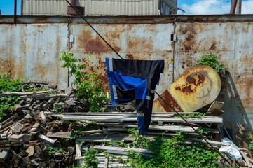 Brightly colored clothing is hanging on a line in an urban setting with rusted structures and lush...