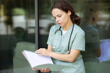 Dark-haired female doctor reading medical case and looking involved