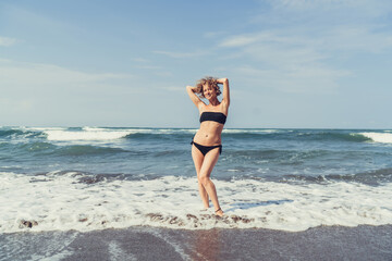 Carefree young woman stretches arms on shoreline, embodying tech-free joy, self-acceptance and...