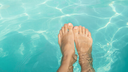 Relaxing by the pool on a summer retreat while dipping feet in clear water