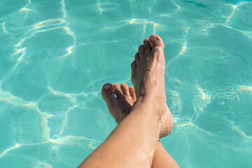 Relaxing moment by the pool with bare legs in refreshing water during summer retreat