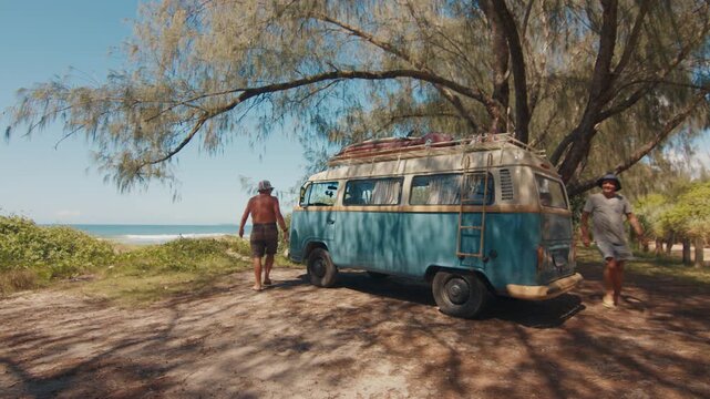 Hippies arrive to the surfing spot by retro classic hippie bus loaded with surfing boards. Hippies travel by retro bus in a search of a surfing spots
