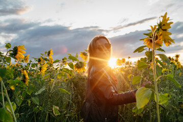A woman walking through a field of sunflowers
