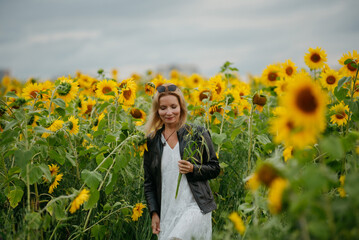 A woman walking through a field of sunflowers