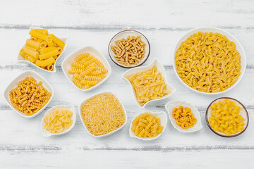 Pasta. Various kinds of uncooked pasta and noodles over wooden background