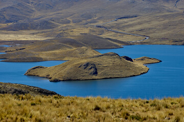 Deep blue waters embrace golden highland hills at Lagunillas Lake near Puno — a serene Andean sanctuary of beauty and calm