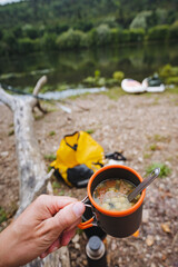 Delight in a cozy warm drink while seated beside the serene waters, creating a truly tranquil camping experience that connects you with nature and offers moments of peaceful reflection