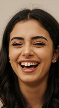 Joyful Laughter: A close-up portrait of a young woman captured in a moment of genuine, unrestrained laughter, her eyes crinkling with delight and her smile radiating warmth and happiness.