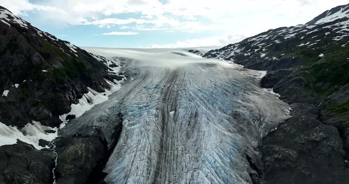 Striking scenery of a huge glacier among the rocks. Drone footage over the ices in Alaska wilderness.