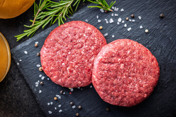 Raw burger beef patties on cutting board on black table. Top view.