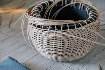 Obraz premium Rattan basket in the process of weaving. A woman's hobby. Natural textures and patterns that create a rustic and organic aesthetic. Perfect for home decor, storage, and organization
