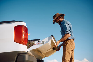 Happy farmer with pick-up truck in field.
