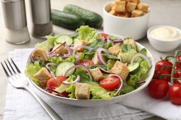 Delicious salad with croutons and vegetables served on light grey table, closeup