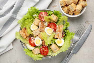 Delicious salad with croutons, chicken, quail eggs, tomato and cheese on grey table, flat lay