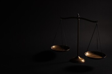 Golden scales of justice on black background, space for text