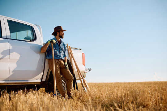 Full length of farmer taking break while working in field.