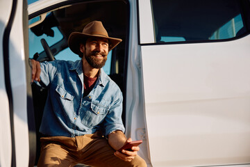 Happy farm worker in pick-up truck using cell phone and looking away. © Drazen