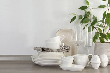 Different clean white dishware, glasses and houseplant on counter in kitchen