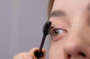 Young Woman Applying Mascara to Enhance Eyelashes. 