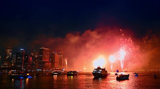 Watching spectacular fireworks in New York. Numerous boats are on the riverscape at night.