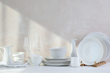 Different clean white dishware and glasses on counter in kitchen, space for text