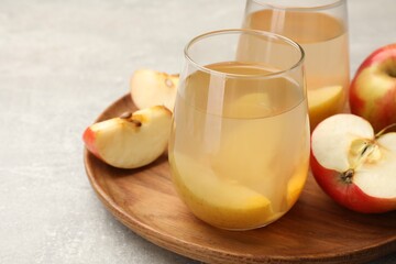 Tasty compot in glasses and fresh apples on grey table, closeup