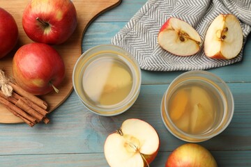 Tasty compot in glasses, fresh apples and cinnamon on light blue wooden table, flat lay