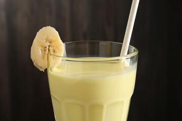 Tasty banana milkshake in glass on blurred background, closeup