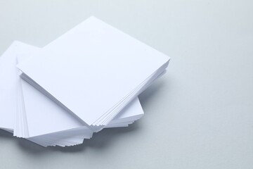 White note papers on light grey background, closeup. Space for text