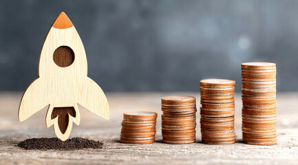 Rocket on top of stacks of coins and representing business growth and financial success
