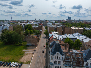 Fototapeta premium Scenic aerial view of Riga, Latvia, featuring Jugendstil buildings, the Riga TV Tower, green spaces, urban infrastructure, and a partly cloudy sky.