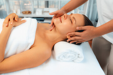 Caucasian woman enjoying relaxing anti-stress head massage and pampering facial beauty skin recreation leisure in dayspa modern light ambient at luxury resort or hotel spa salon. Quiescent