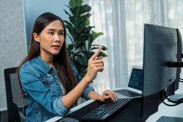 Young Asian girl of IT developer pointing online information on pc with coding program data...