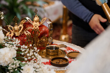Orthodox Wedding Ceremony Ritual with Golden Crowns and Red Cloth: Close-Up of Symbolic Rings,...