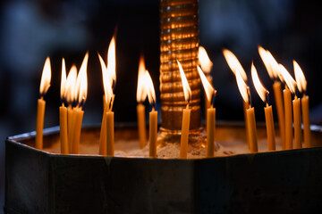 Illuminated Candles in Church with Golden Flames, Religious Votive Offering, Dark Atmospheric...