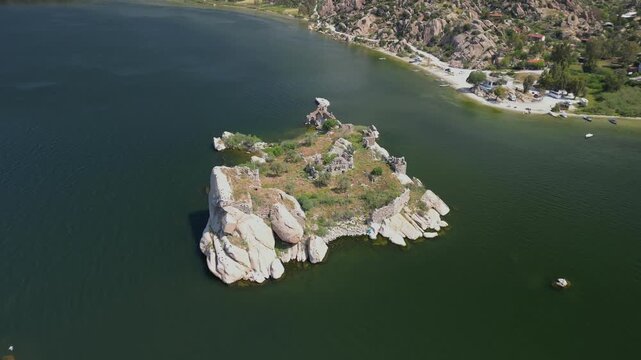 Remains of stone buildings on an island in Lake Bafa, Turkiye. Surrounded by calm water. Aerial view captures the blend of Turkish history and nature in this quiet region.