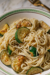 zucchini with angel hair pasta in elegant bowl with green greek key