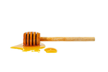 Honey puddle with wooden honey spoon isolated on white.
