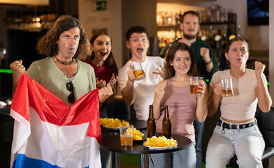 Fans of the Netherlands national team spend time in a bar, shouting chants, supporting their favorite team