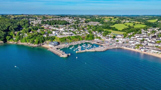 A distant rotating aerial view across the harbour in the early morning in Saundersfoot, South Wales in summertime