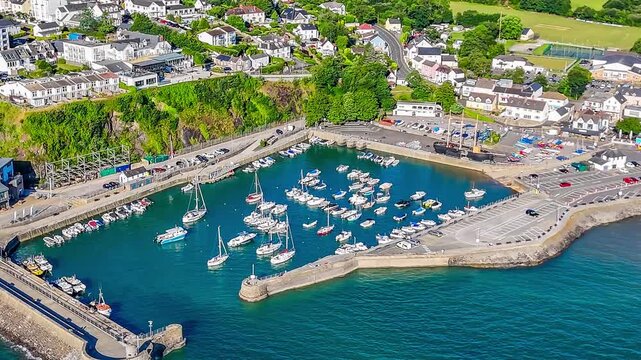 A close up rotating aerial view across the harbour in the early morning in Saundersfoot, South Wales in summertime