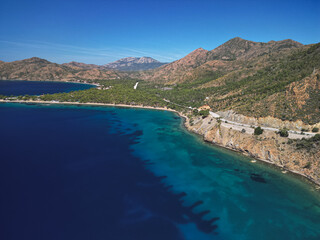 Obraz premium Aerial view reveals secluded natural cove featuring brilliant emerald waters surrounded by lush Mediterranean vegetation creating hidden coastal gem