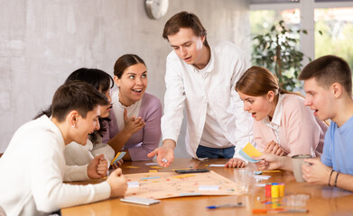 Group of happy young people playing board game
