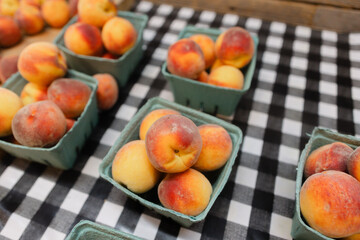 Fresh peaches arranged in baskets on a checkered tablecloth at an outdoor market