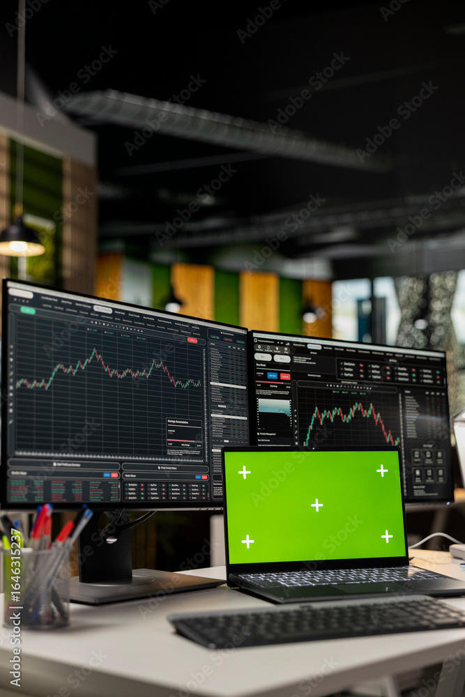 Poster close up of mockup laptop on desk and computer displaying candlestick graphs with stock market share