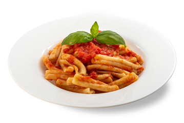 Caserecce Italian macaroni pasta topped with red tomato sauce and fresh basil leaves on a white plate isolated