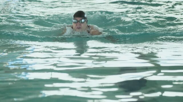 Professional swimmer performing butterfly stroke in a swimming pool. Concept of sport, training, fitness, endurance, aquatic exercise, and healthy lifestyle.