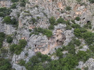 Aerial view of the Kaunos necropolis near Dalyan Turkiye rock cut tombs pierce steep cliffs above green forest dramatic landscape perfect for heritage projects documentaries and cultural tourism