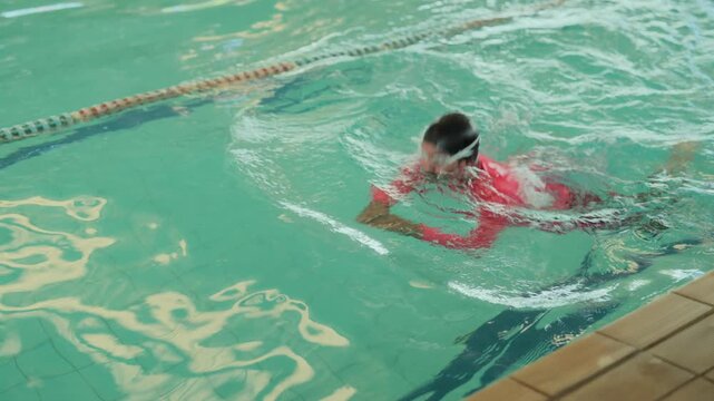 Swimmer in Red Shirt Training in Indoor Pool